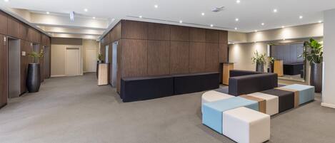A modern living room with a sectional sofa, a flat-screen TV, and built-in wooden cabinets.