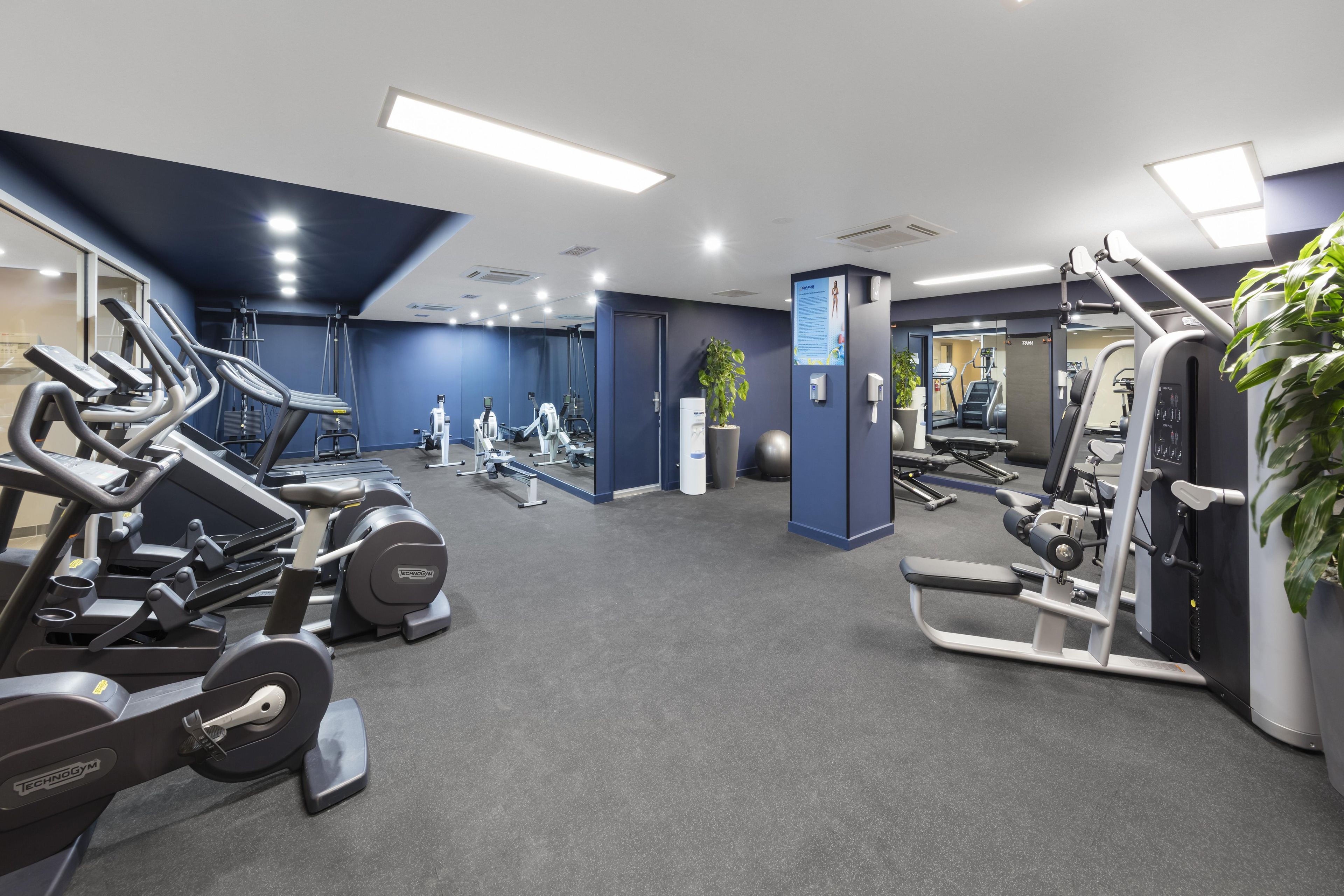 A gym with cardio machines, weightlifting equipment, and a mirror.