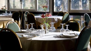 Un espace repas avec des tables rondes, des chaises et un vase rempli de fleurs.