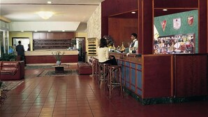 Un hall d’entrée avec un comptoir de réception, un espace salon et un bar.