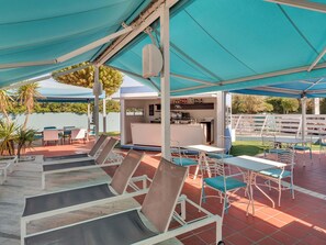 A covered outdoor seating area with tables and chairs, a bar area, and a view of the surrounding landscape. - B&B Hotel Chioggia Airone (Chioggia)