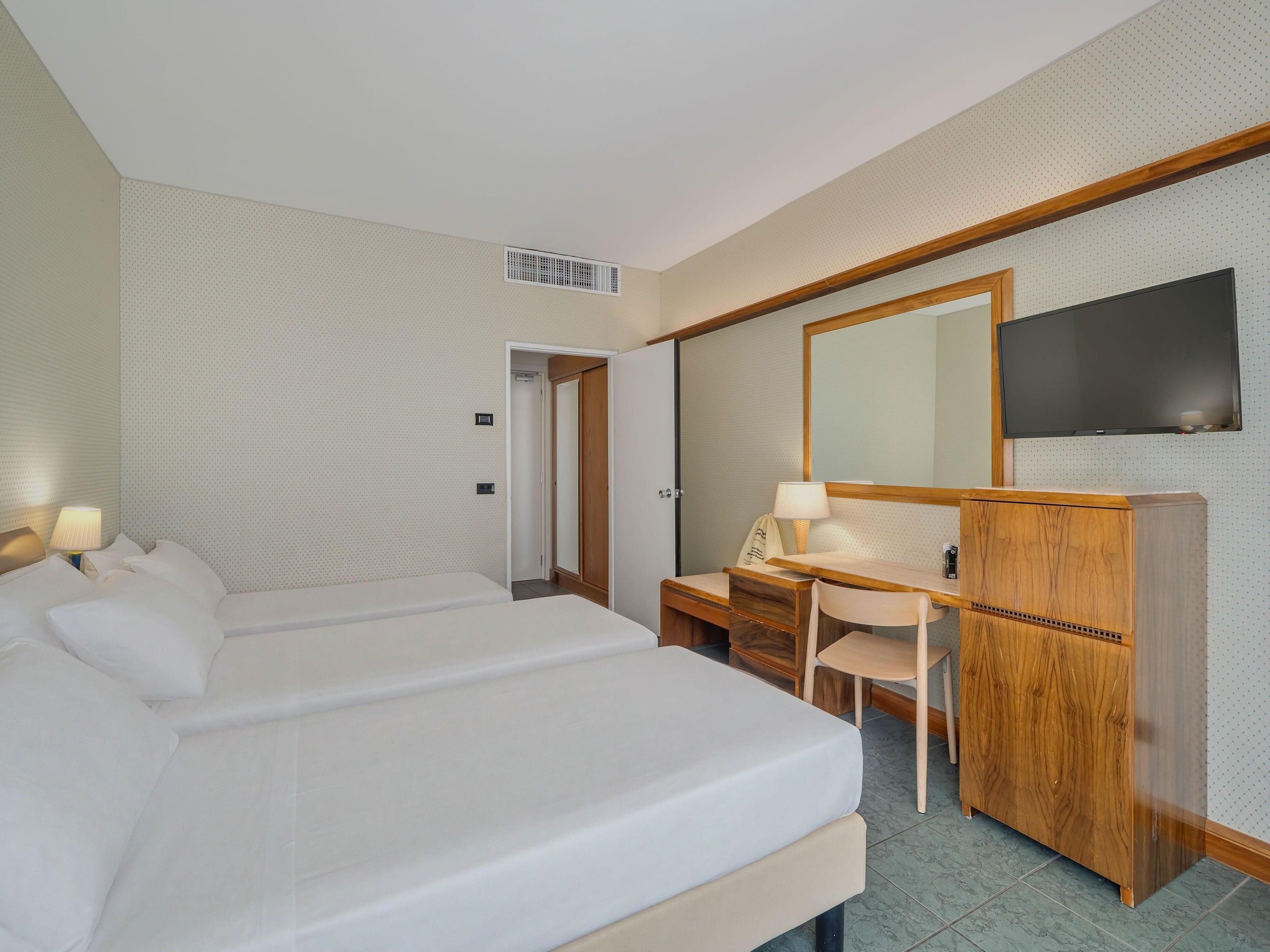Une chambre d’hôtel équipée d’un lit, d’un bureau, d’une chaise, d’une télévision et d’une armoire.