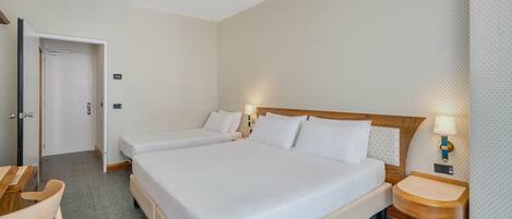 Una habitación de hotel con una cama grande, dos mesitas de noche con lámparas, una silla de madera y una puerta.