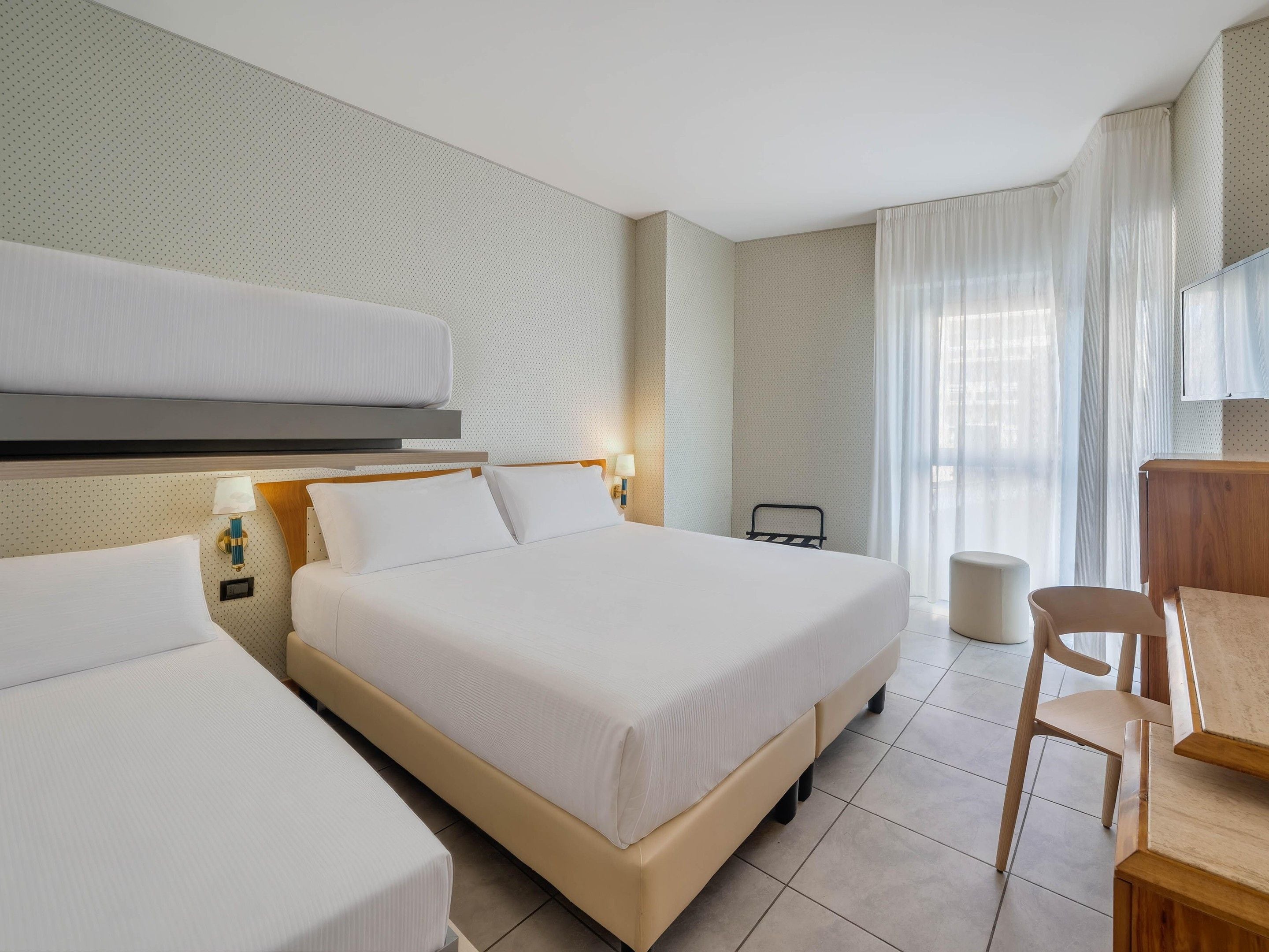 Une chambre d’hôtel avec deux lits, un bureau et une chaise.