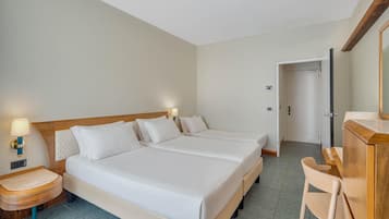 Ett hotellrum med en dubbelsäng, sängbord, ett skrivbord och en stol.