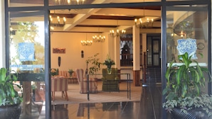 A hotel lobby with a polished floor, seating area with chairs and tables, and potted plants.