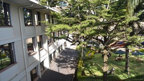 A courtyard with a building on one side, trees, and outdoor seating areas.