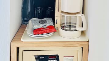 A coffee machine, a bottle of water, a coffee pod, and a small shelf with a pot labeled "RÍVOLJ SELECT HOTEL".