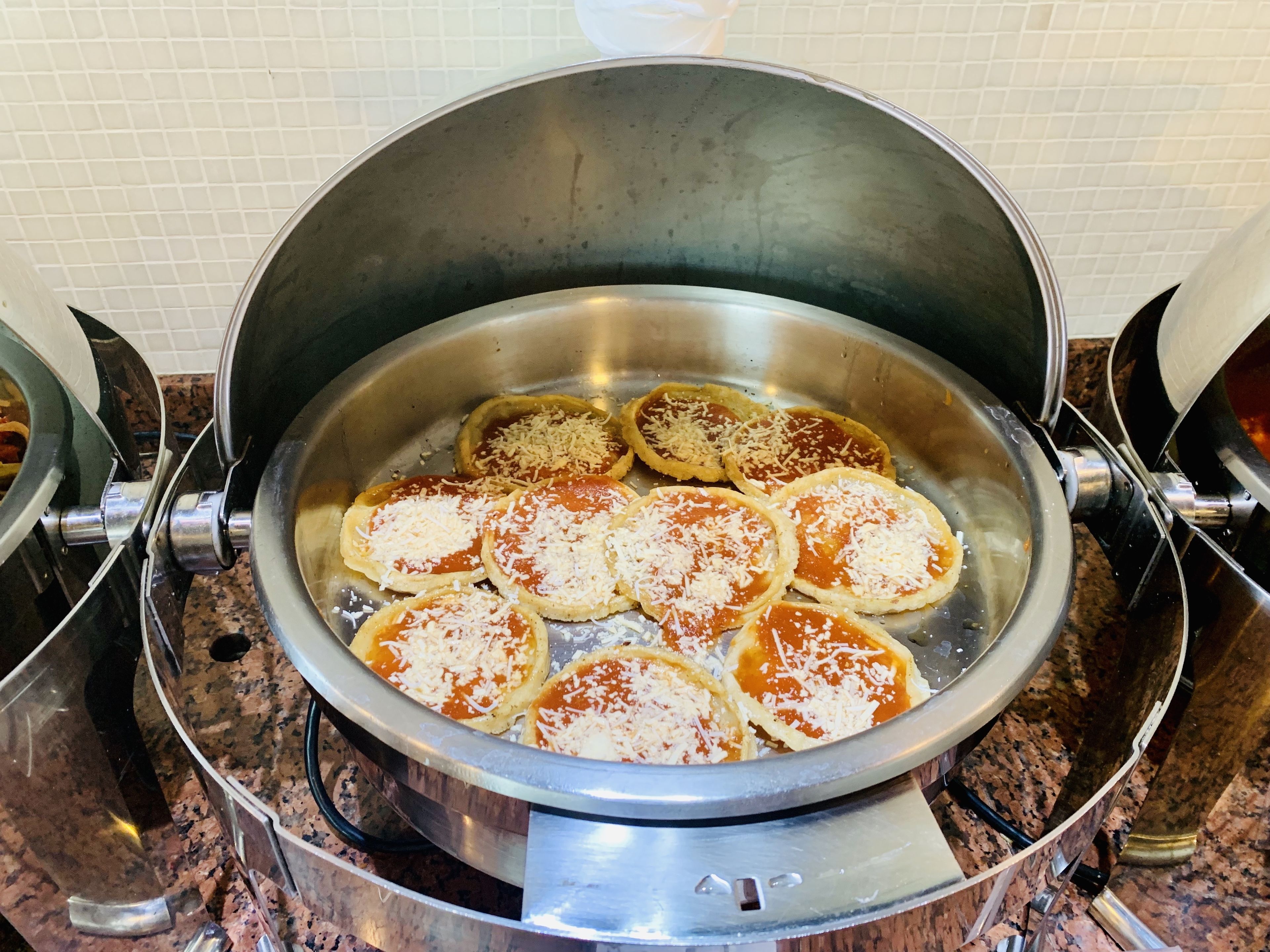 Una olla de acero inoxidable con varias bases de pizza sobre un fogón.