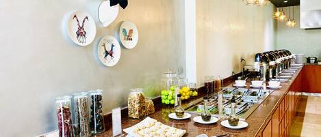Buffet montado com diversos alimentos e pratos decorativos no balcão.