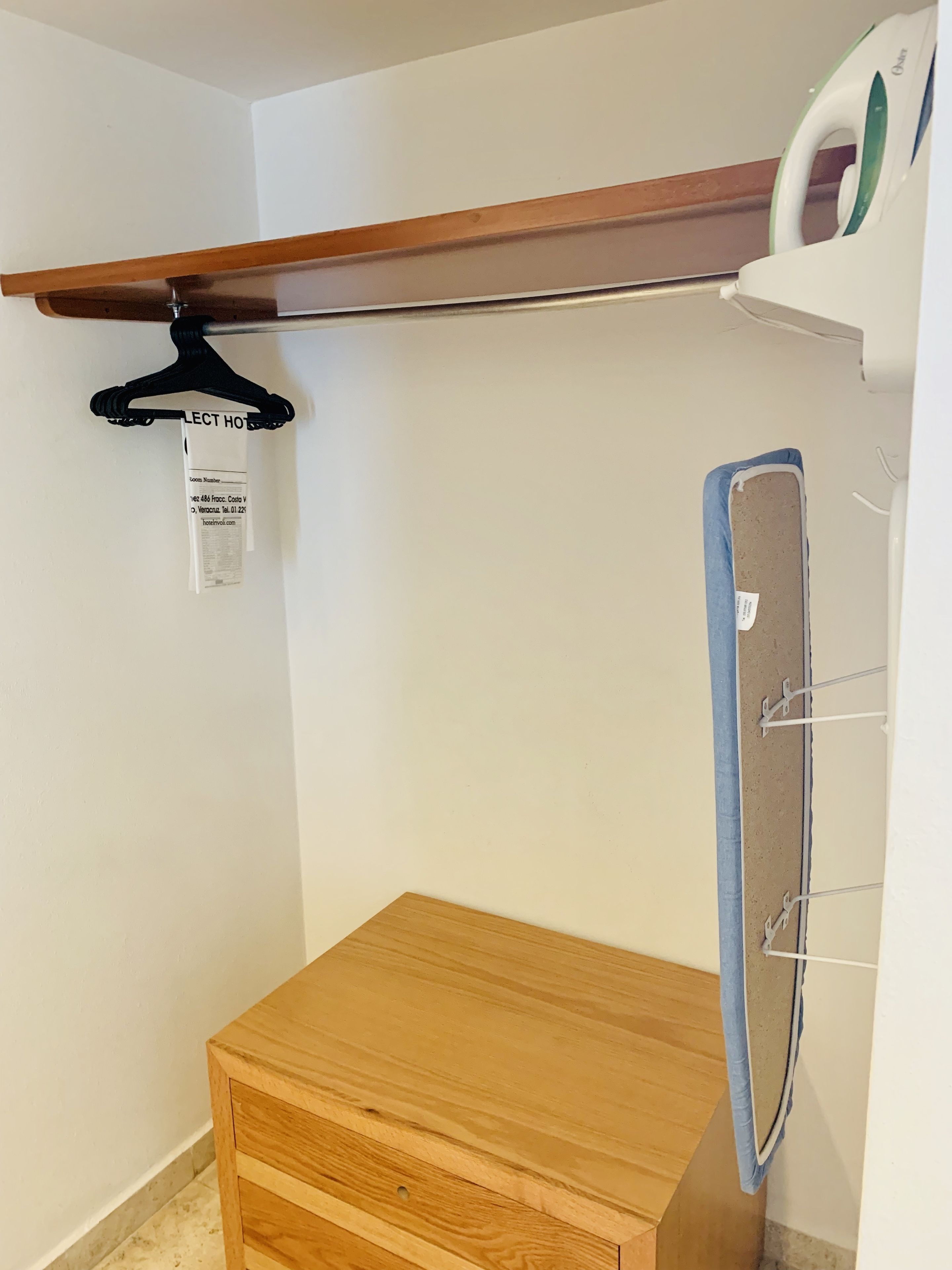 A small wooden cabinet with a hanging garment rack above it.