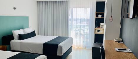 Habitación de hotel con dos camas, un escritorio, una silla, una cafetera y un teléfono.