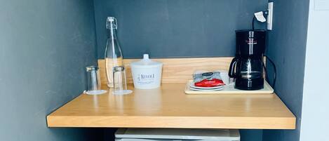Uma cozinha compacta equipada com micro-ondas, cafeteira e mini-geladeira.