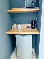 Una kitchenette compacta con microondas, cafetera y un refrigerador pequeño.