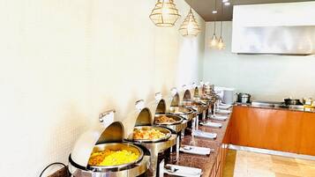 A buffet setup with multiple food stations, a counter with a cash register, and hanging pendant lights.