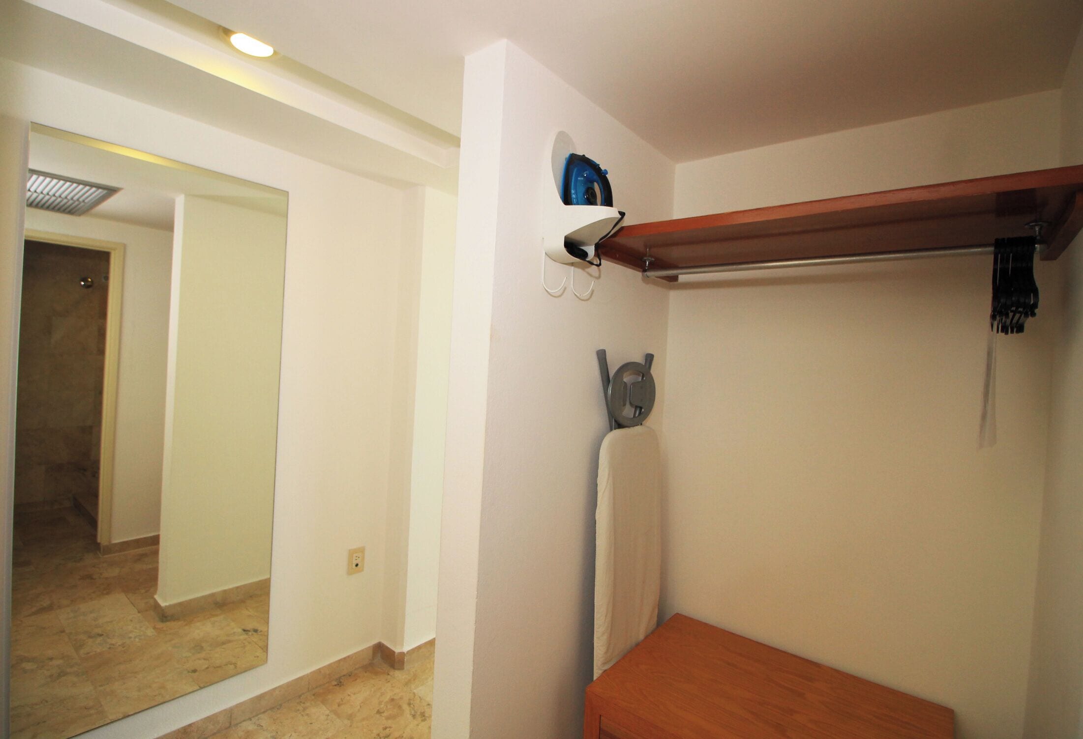 A bathroom with a wooden bench, a towel rack, and a mirror.