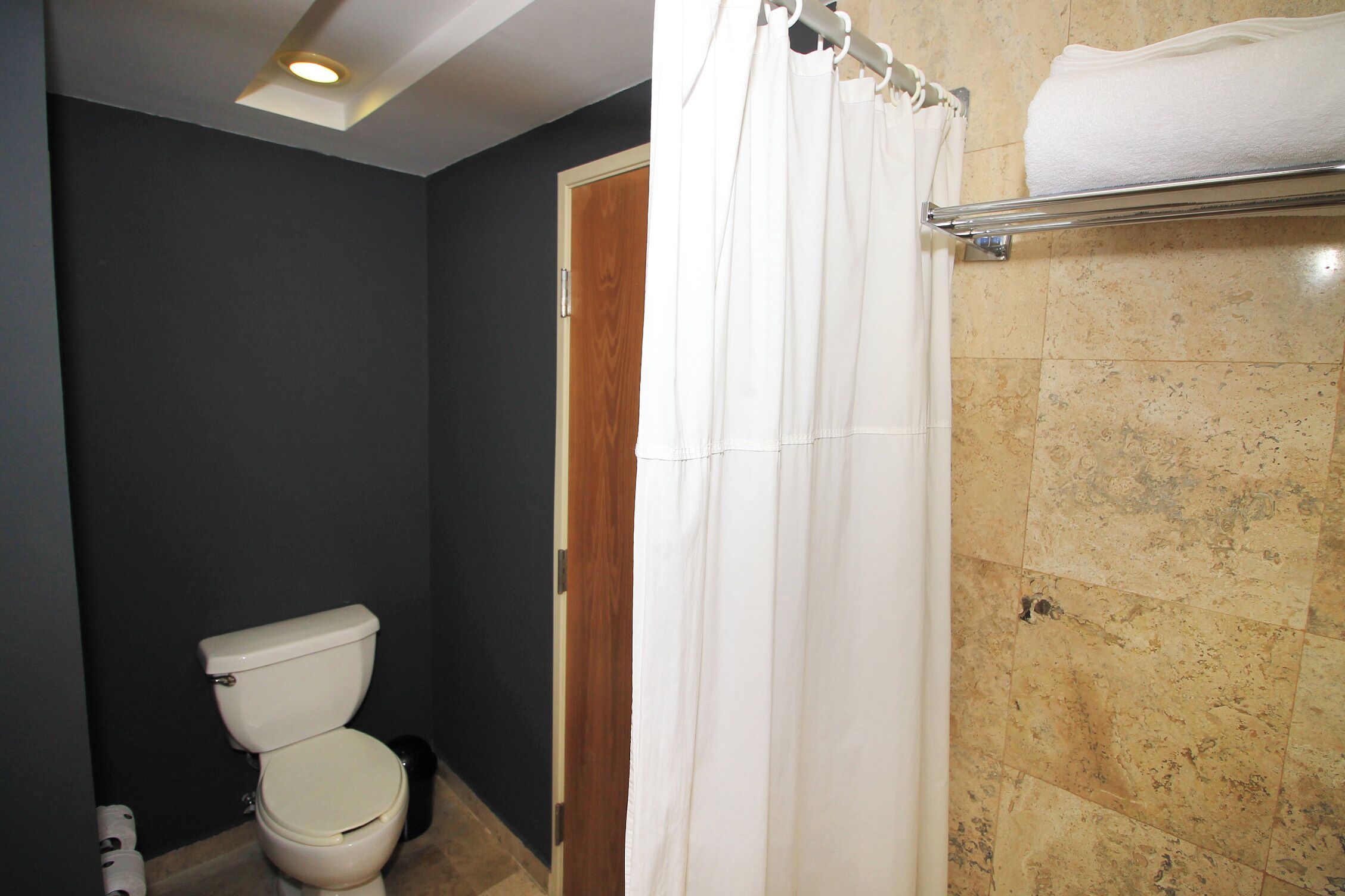 Un baño con inodoro, cortina de ducha y toallero.