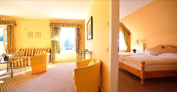 Een hotelkamer met een slaapbank, een stoel, een bed en een klein tafeltje.