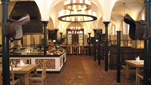 Interior de un restaurante con una isla central, techos altos en arco y un candelabro.