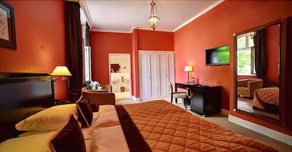 Una habitación de hotel con una cama grande, un escritorio, una silla y un televisor.