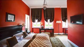 A hotel room with a large bed, a desk, and a television.