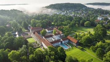An aerial view of a large estate with multiple buildings, a swimming pool, and surrounding greenery.