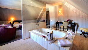 Een moderne hotelkamer met een ruim bad, een eethoek en een aparte zithoek.
