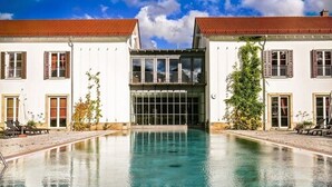 Een zwembadgedeelte met twee gebouwen, elk voorzien van een rode pannendak en witte muren.