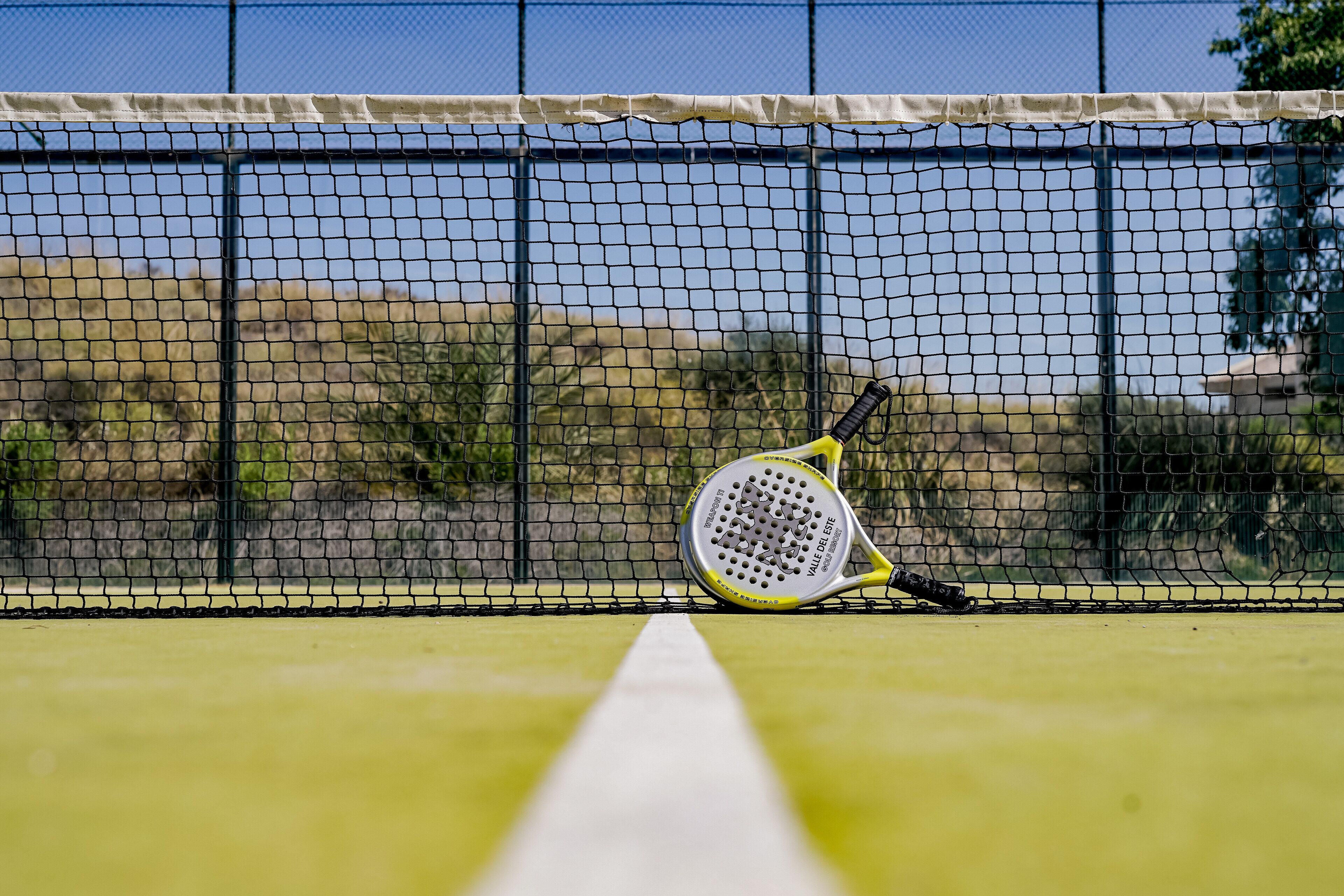A tennis court with a net and a tennis racket leaning against it.