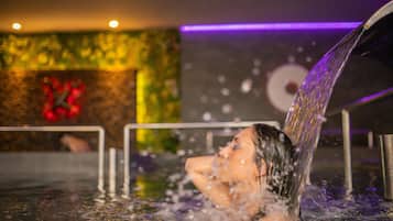 A person in a hot tub with water flowing over them.