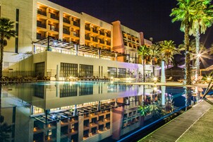 Un hotel con piscina, varios balcones y palmeras.