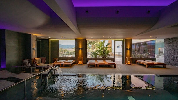 Zona moderna de piscina interior con sillones de descanso y vistas a las montañas.