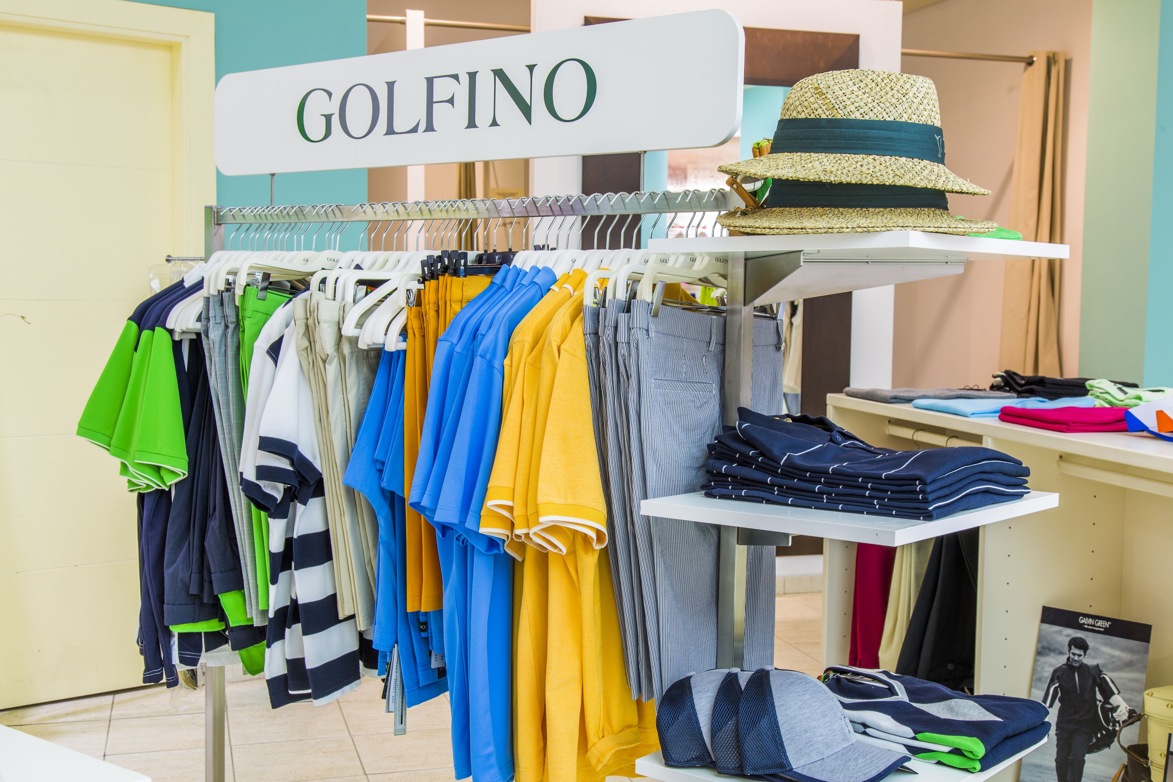 A clothing store named GOLFINO with racks of colorful shirts and folded pants.