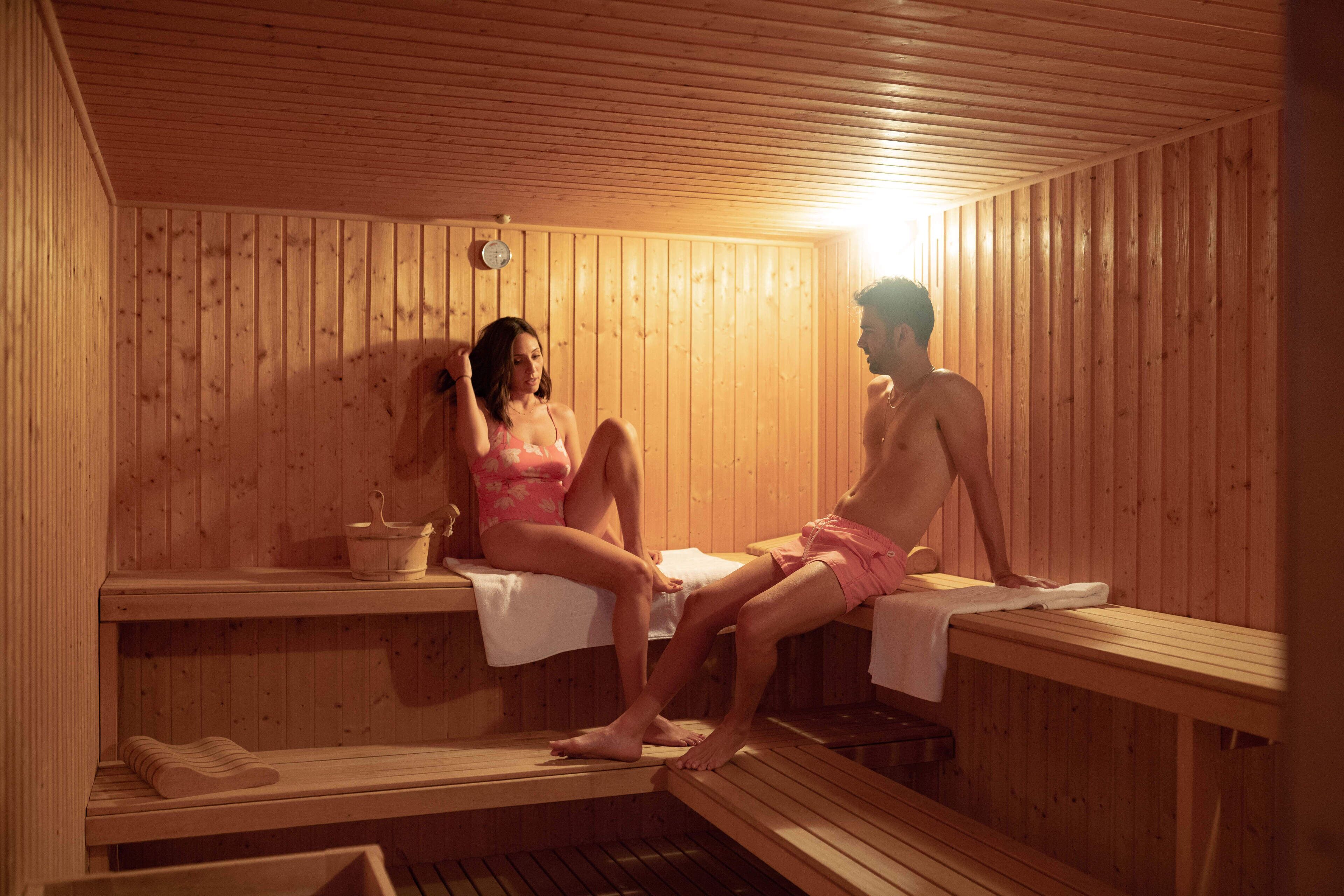 A sauna with wooden benches and benches, a bench with a towel, and a bucket.