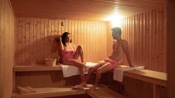 A sauna with wooden benches and benches, a bench with a towel, and a bucket.