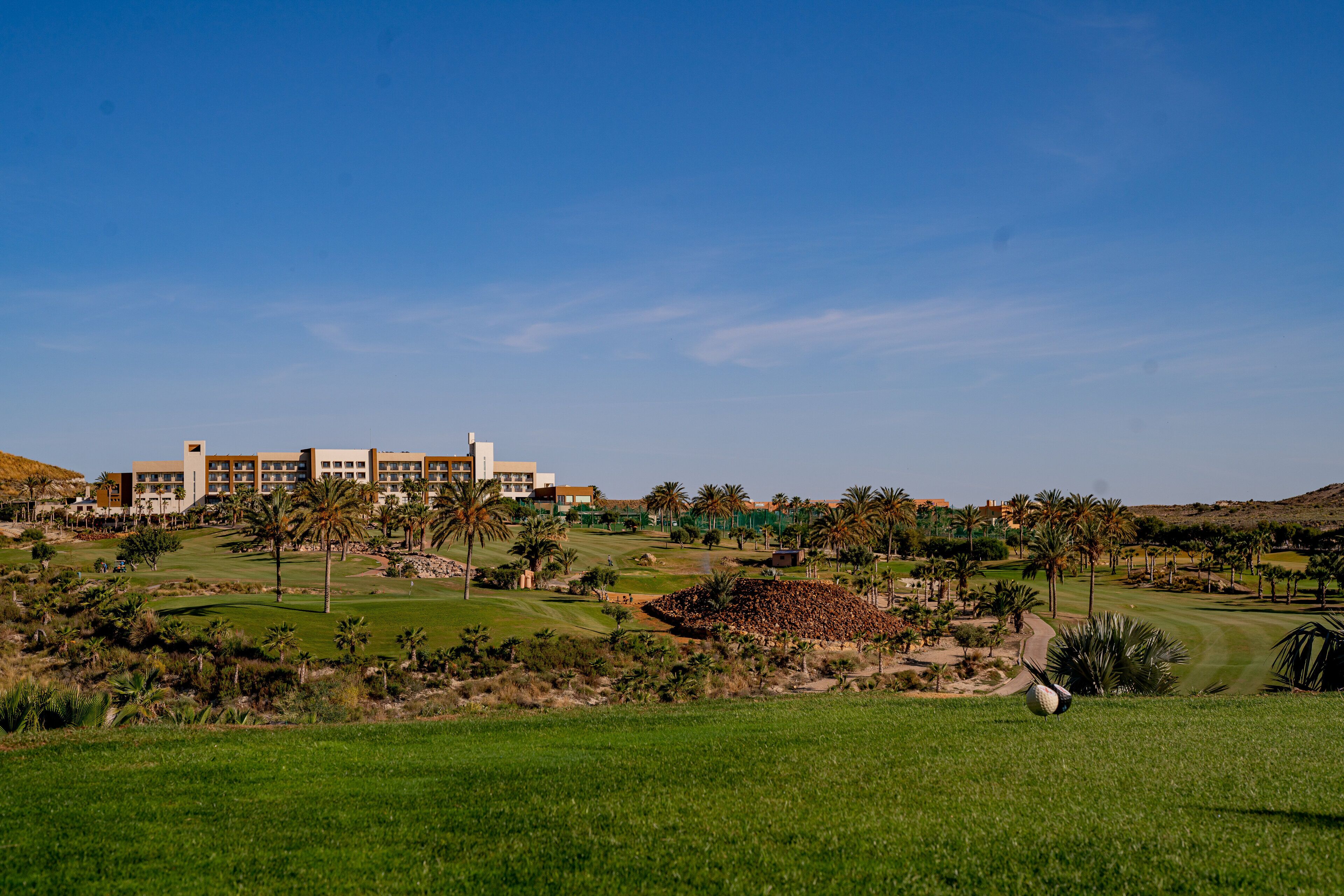 A golf course with a large building in the background.