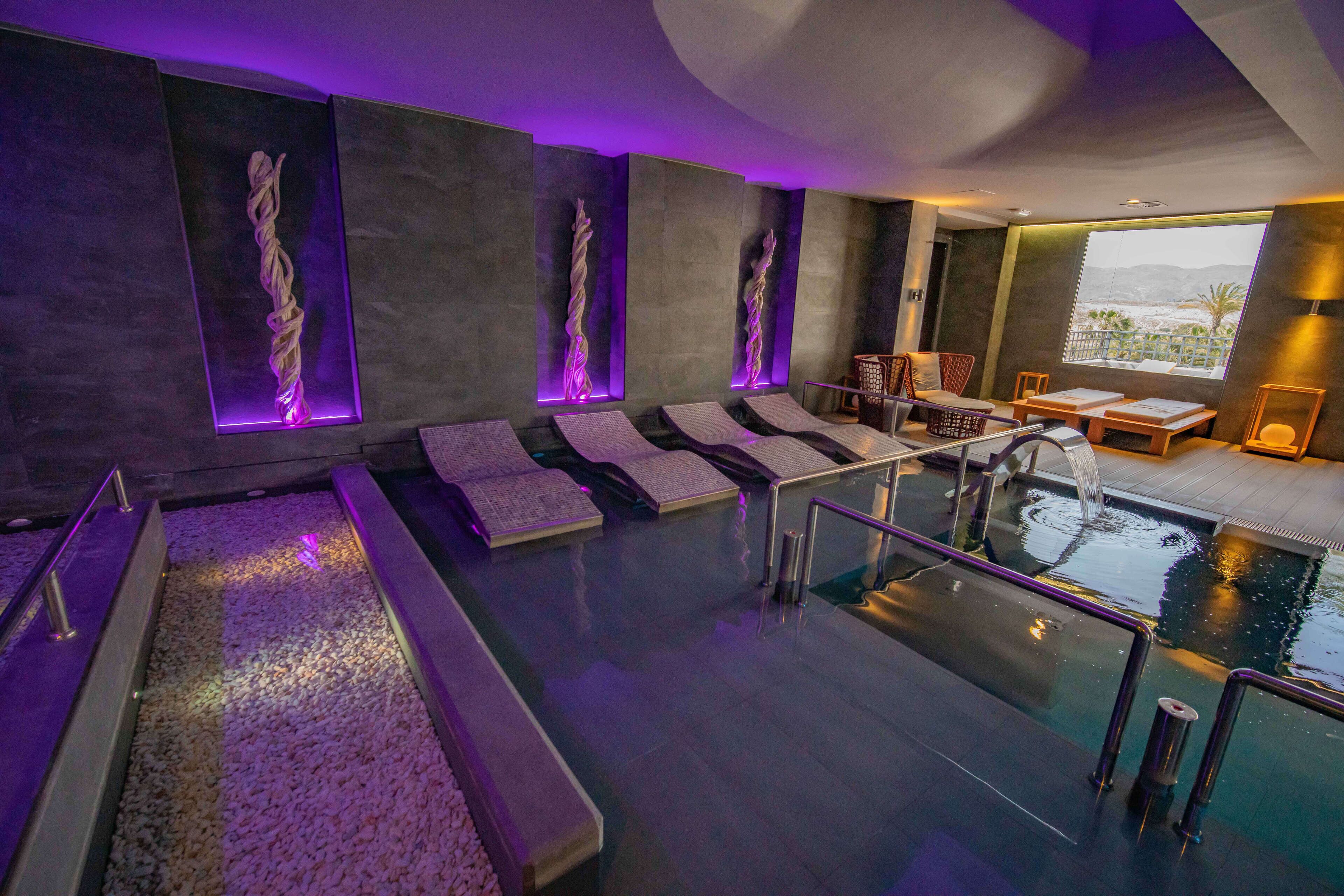 A modern spa area with a pool, seating, and a view of the outdoors.