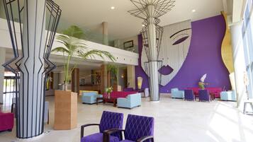 A spacious lobby with a modern design, featuring a reception desk, seating area, and a large abstract wall art piece.