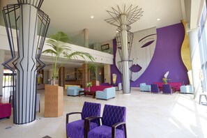 A spacious lobby with a modern design, featuring a reception desk, seating area, and a large abstract wall art piece. - Hotel Valle del Este Golf Spa (Vera)