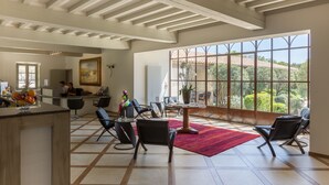 Una habitación amplia con techo alto, ventanas grandes y vistas al exterior.