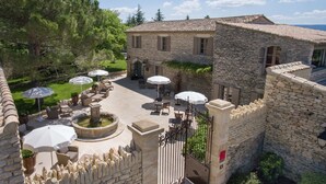 Un edificio de piedra con patio, mesas al aire libre y una fuente.