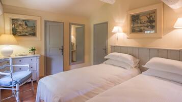 Un dormitorio con dos camas, un aparador, una silla y dos lámparas de pared.
