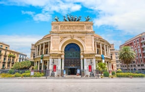 Stunning historic building with a grand central archway, flanked by classical columns and ornate details.
