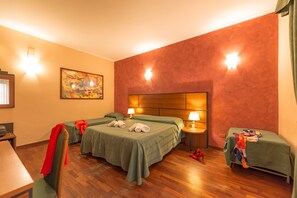 Two single beds, a desk, and a small table with chair, complete with a lamp and a unique painting.