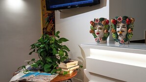 Une pièce avec un téléviseur fixé au mur, une plante, des livres et des objets décoratifs sur une table.
