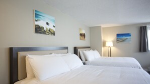 A hotel room with two beds, a nightstand, and wall art.