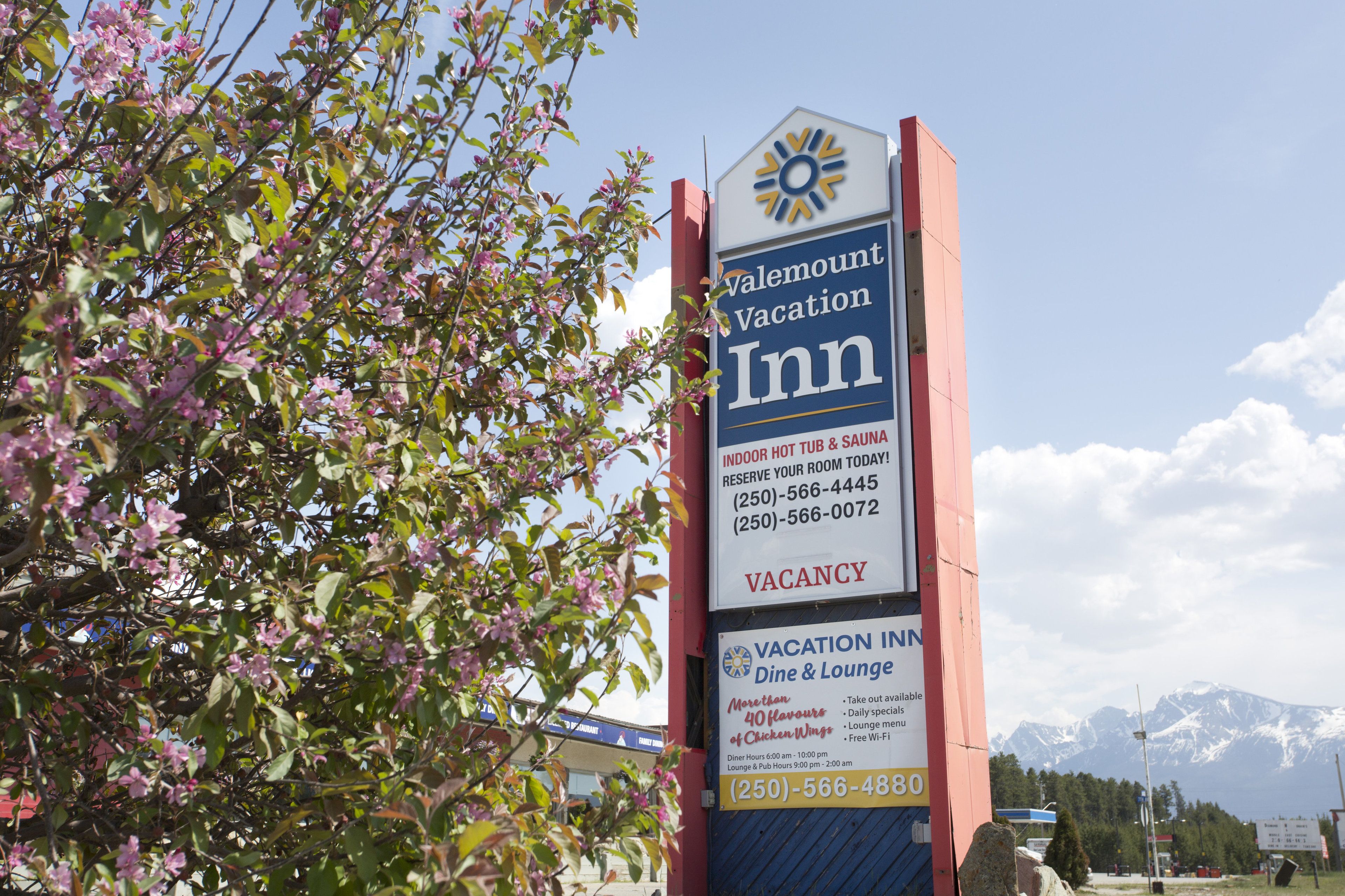 Une enseigne indiquant le Valemount Vacation Inn, avec une publicité pour un bain à remous intérieur et un sauna, ainsi que la mention « chambres disponibles » et les numéros de téléphone à contacter.