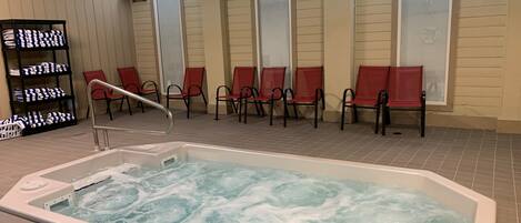 Un espace détente avec un jacuzzi, des chaises rouges et un porte-serviettes.