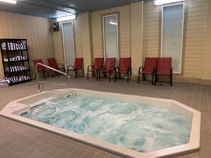 A spa area with a hot tub, red chairs, and a towel rack.