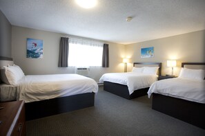 A hotel room with two beds, a desk, and a window with curtains.